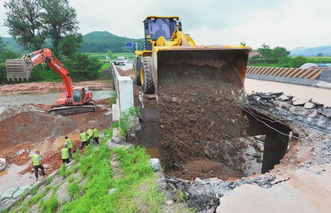 圖為丹東鳳城市丹霍線薛禮站南橋水毀錐坡?lián)屝蕃F(xiàn)場，大型機械拆掉橋頭搭板后回填砂石料和水穩(wěn)料。記者 查金輝 攝